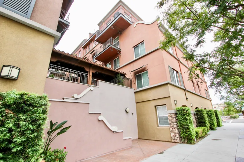 An apartment building with beige and red tones and a patio between the units.