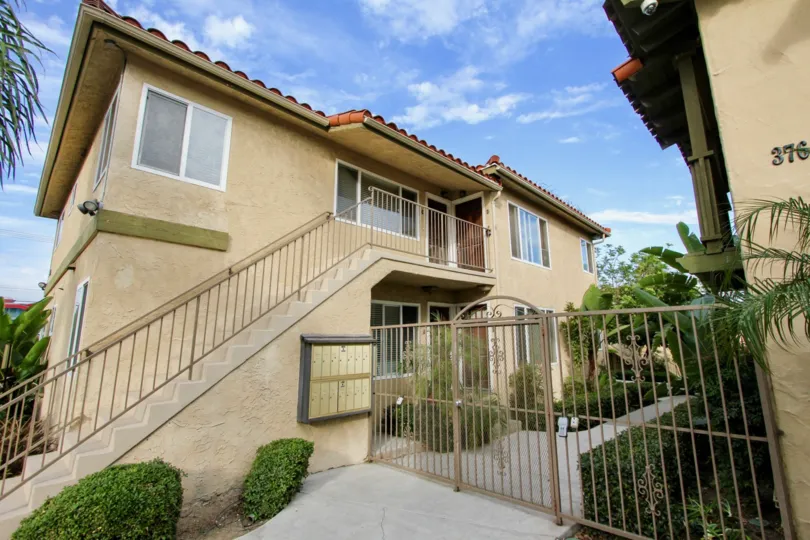 Yellow sand toned apartment compex with a garden, fence and stairs to the upper floor in the La Hacienda Community in North Park, California