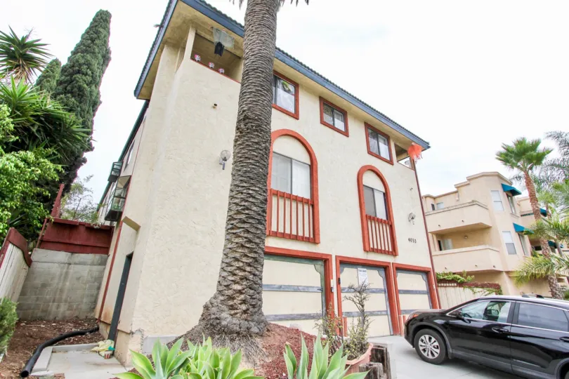 Palm tree in front yard of a white stucco multi-level condo complex with orange trim in Louisiana 8.