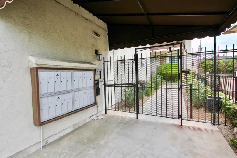 LOUISIANA AT THE PARK, North Park, CA, The entrance of a building, a black gate and malboxes for the buildings, a little garden.