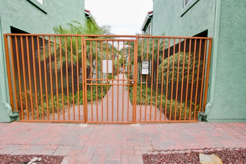 Iron railing gate narrow path landscaped in Majestic Palm.