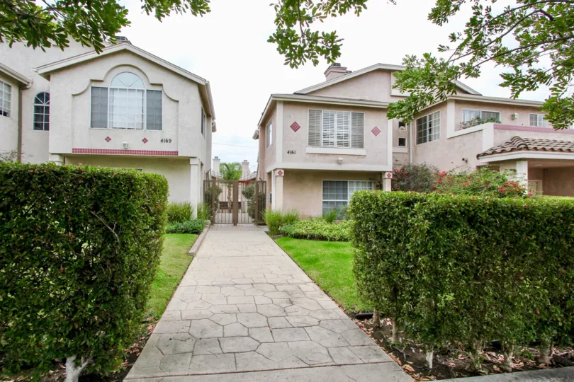 A walkway between two properties with a fence and landscaping at Mardi Gras Villas