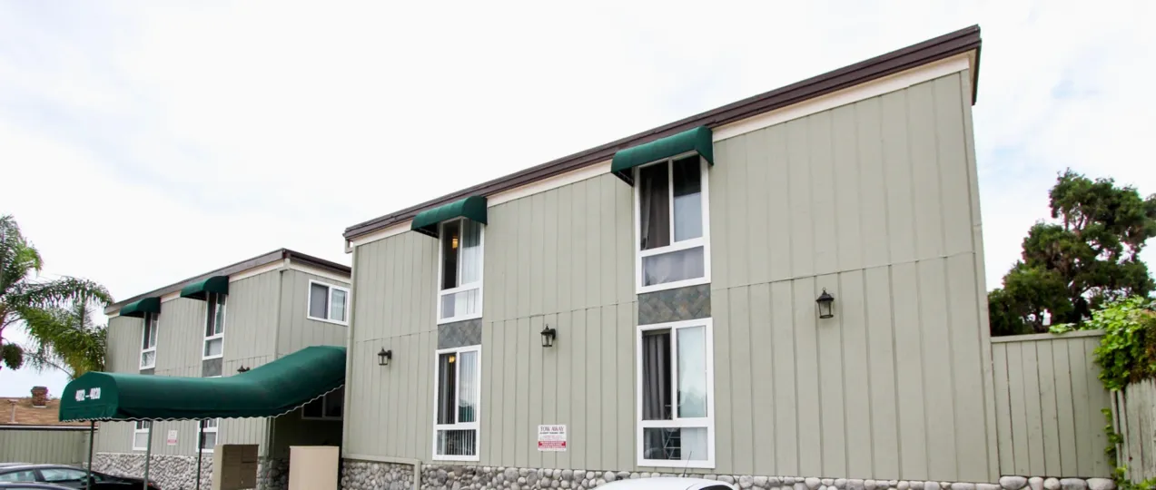 Two story gray housing next to a green tree inside Mississippi Townhomes at North Park ca