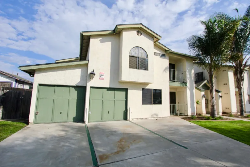 Two closed green wooden garage doors sit in the sun at the North Park Swift condos.