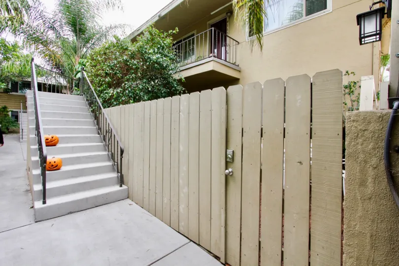 The back of the garden of an apartment complex with pumpkins on the stairs and a balcony in the background in the Pacific Palms Community in North Park, California