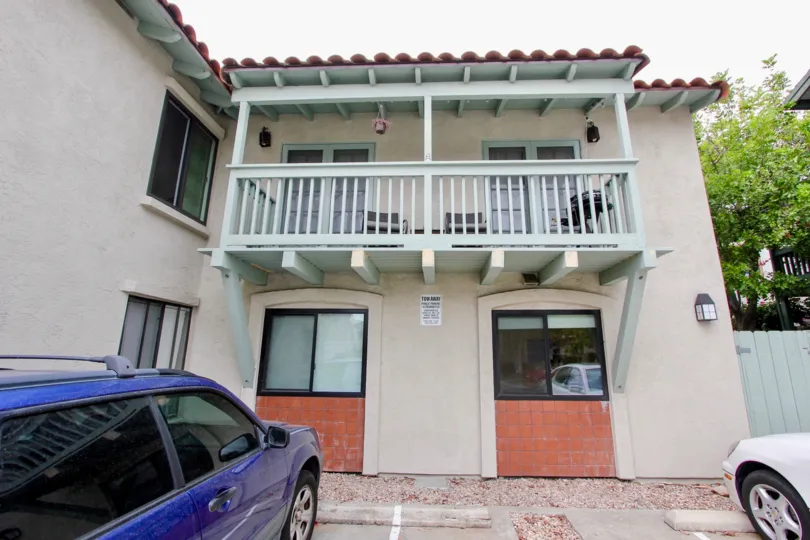 Car is parking in front of the Park Heights and has balcony with chairs