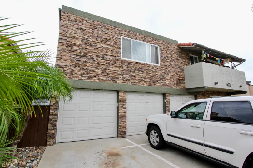 Front of a house with tree garage doors a balcony and some plants in the Rio Grande