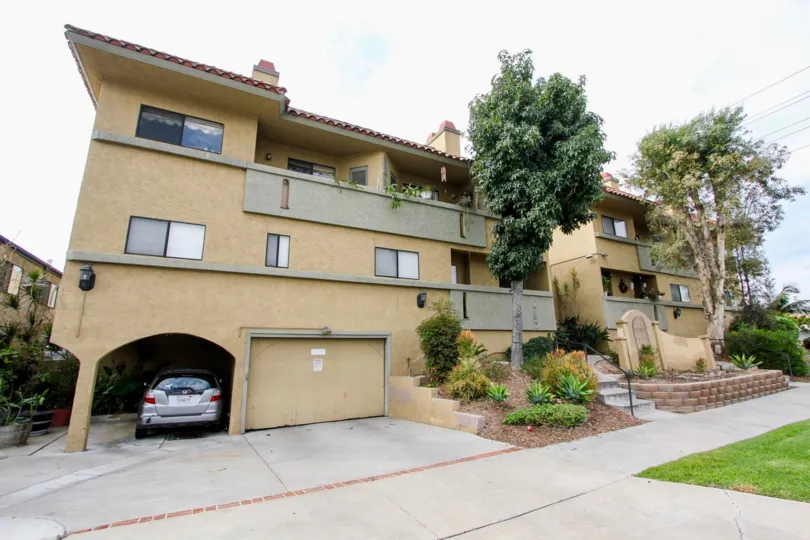 A gray car is parked in a carport next to a garage at the Spanish Oaks I condos/