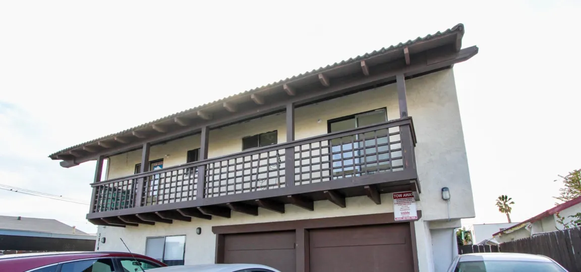 Front of house with long balcony in top floor and two garage doors in bottom level in the Triton Condos