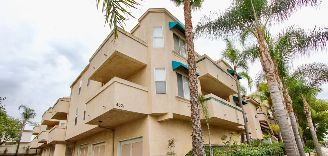 Palm trees lining a three story residential building