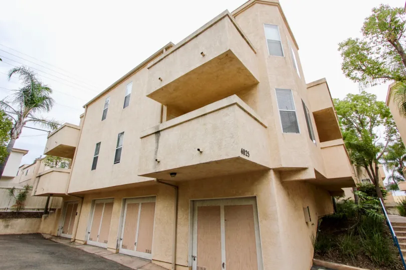 A sand coloured apartment complex with balconies on every floor and garages on gorund level in the Uptown Villas Community in North Park, California