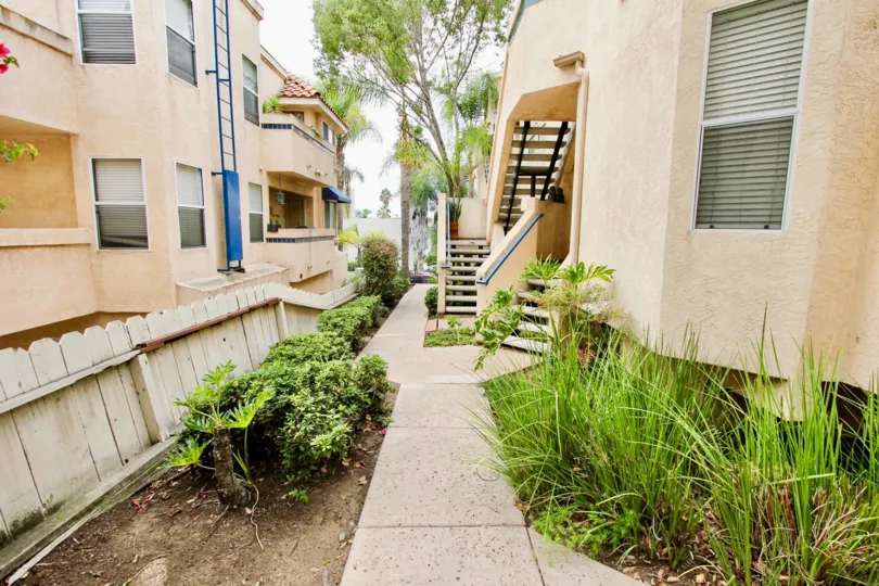 External apartment walkway at Uptown Villas in North Park, CA. Sunny day with palm trees.