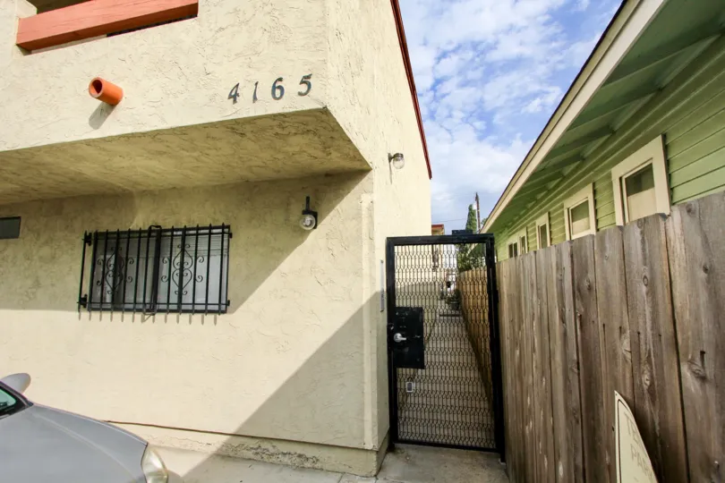Looking between buildings down a narrow alleyway through a black gate in Villa de 33rd in North Park, California