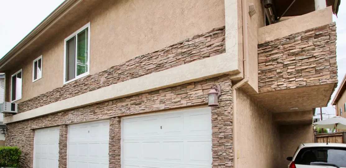 Three white garages on a pink building inside Villas on Idaho at North Park CA