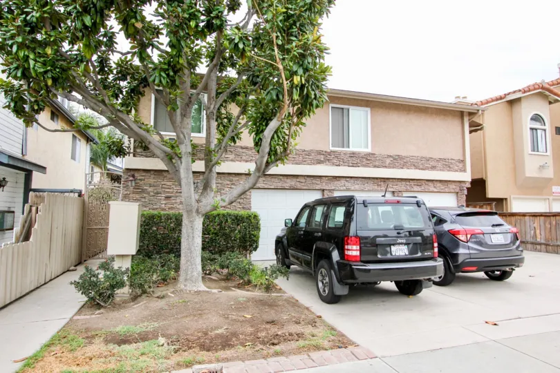 A house with two cars on the front porch and a large tree of Villas on Idaho in North Park, California