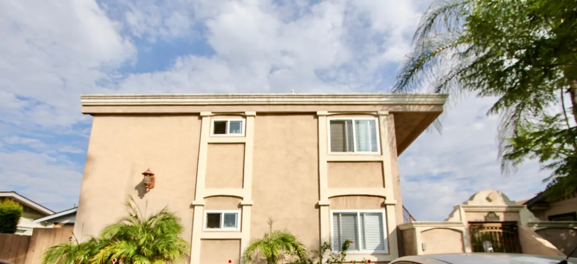 A two story adobe building with palm trees in Wabash Gardens