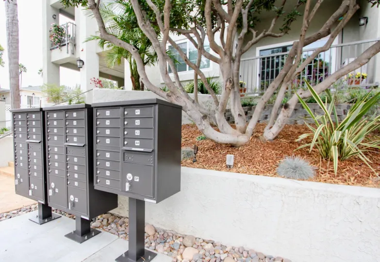 A sunny day in the area of Wilshire on the Park, mailboxes, tree, fence, condo