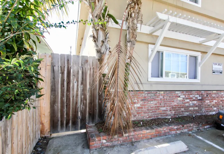 A gate and parking spot with greenery and a window for 4841 Del Monte Ave.