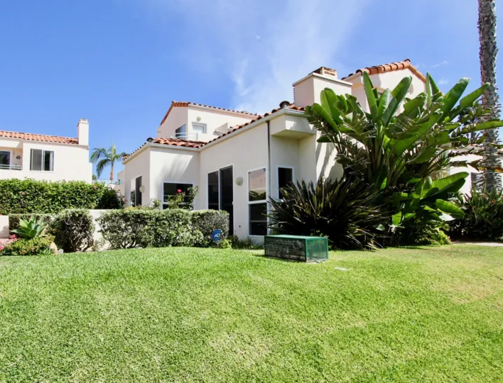 Exterior view of Mediterranean residential complex with tropical landscaping and ADT security protection.