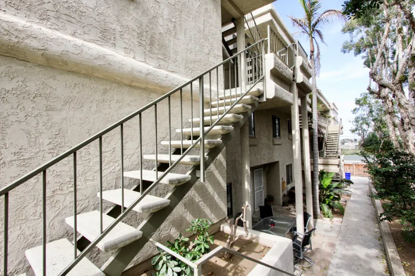 Exterior stairs and stucco exteriors with a fenced in courtyard with tall trees in Brittany Hill, Ocean Beach, CA