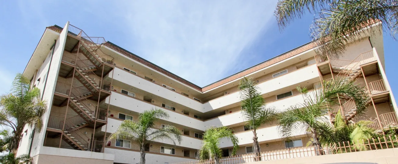The five story building surrounded by palm trees and clears skies.