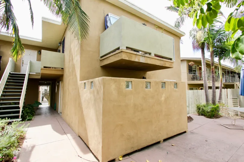 stairs in the side of the building and chair and umbrella in the back side of the building in Mentone Villas