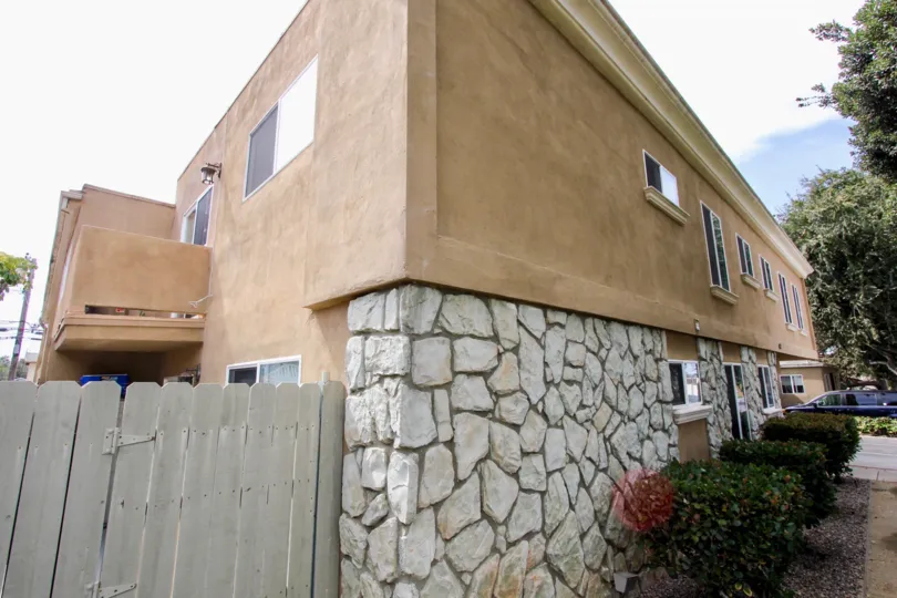 Fence and corner of mixed-siding building in Mentone Villas in Ocean Beach, California.