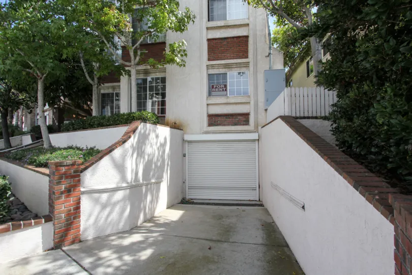 Garage front view with trees and plants near the building in Poinsettia Villas