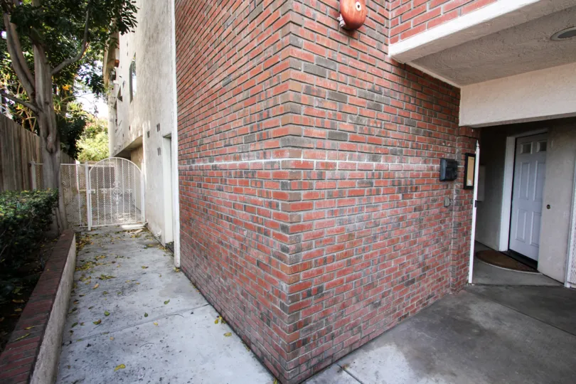 Brick design wall near the building and trees and plance in the side of the building in Poinsettia Villas