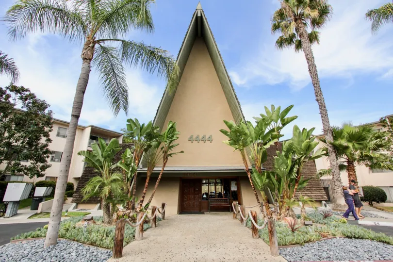 A sunny day in front of Point Loma Villas with several palm trees and bright blue skies