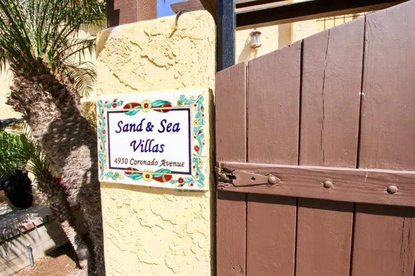 A red, white, yellow and blue sign reads "Sand and Sea Villas"