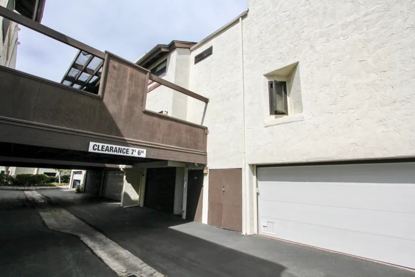 A sign indicates there is a low clearance under a bridge between two buildings at Sea Colony condos