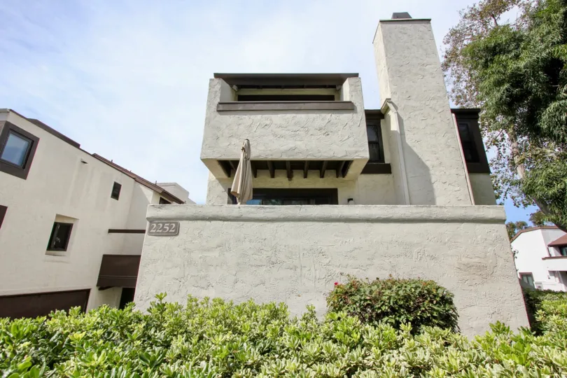 Two story white building with plants in front of it in Ocean Beach CA at Sea Colony
