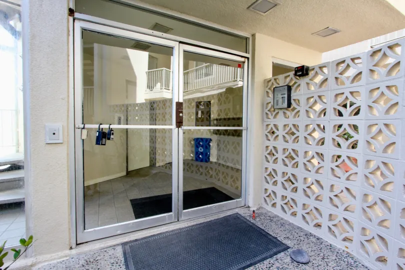 Aluminium fabricated glass door of building in the Sunset Towers with small plants.