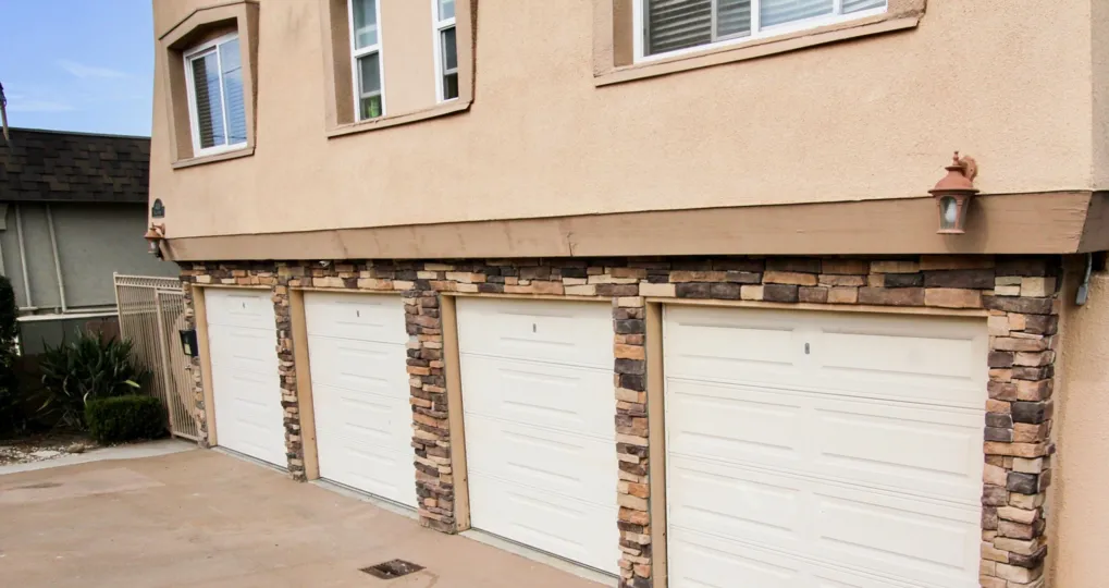 A tan and brown stone surround is seen around white garage doors at Temecula Heights