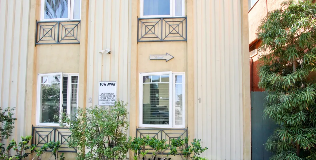 a house with a tow away sign in front and a little shrub garden in The Beach House community