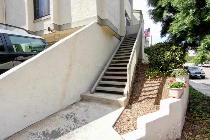 Trees and plants near the entrance stairs and car parked near the building in Worden Street Condos
