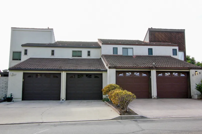 Concrete driveways and brown garage doors at El Camino Villa in Oceanside, California