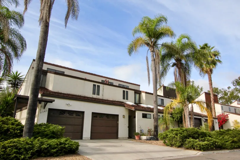 An El Camino Villa residential building with palm trees and garages in Oceanside California