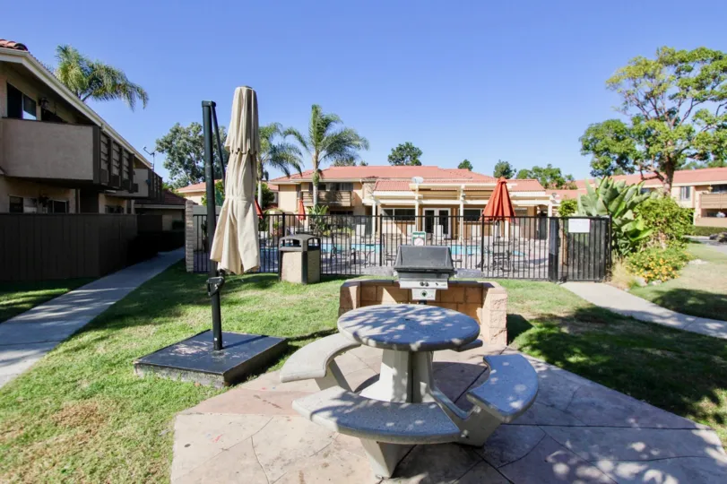 A sunny day in the area of Forest Glen, outside, picnic table, umbrella, pool palm tree, grass