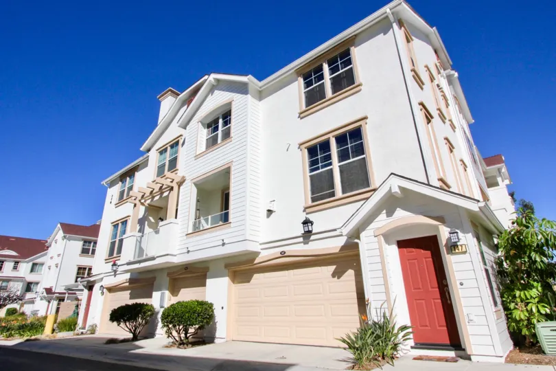 The outside of a unit at the Harbor Cliff condominiums with private entrance, garage, and balcony under a blue sky.