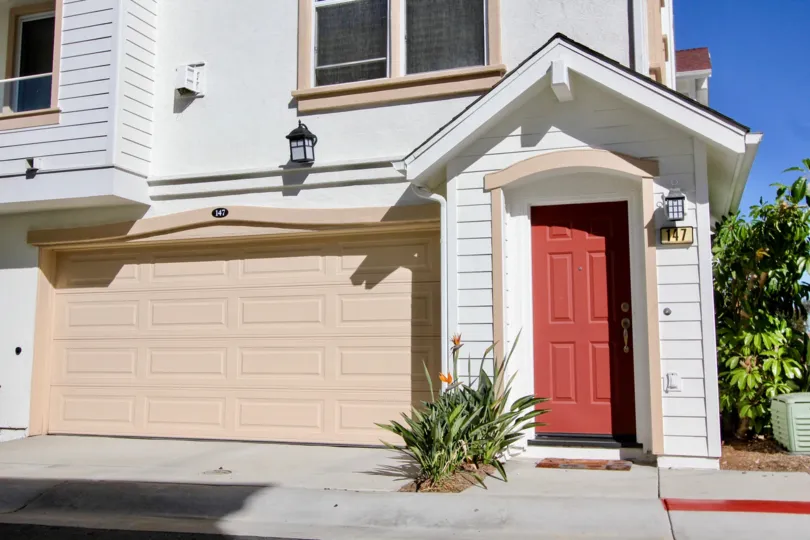 A house has a red door and a pink garage in the Harbor Cliff community in Oceanside, California.