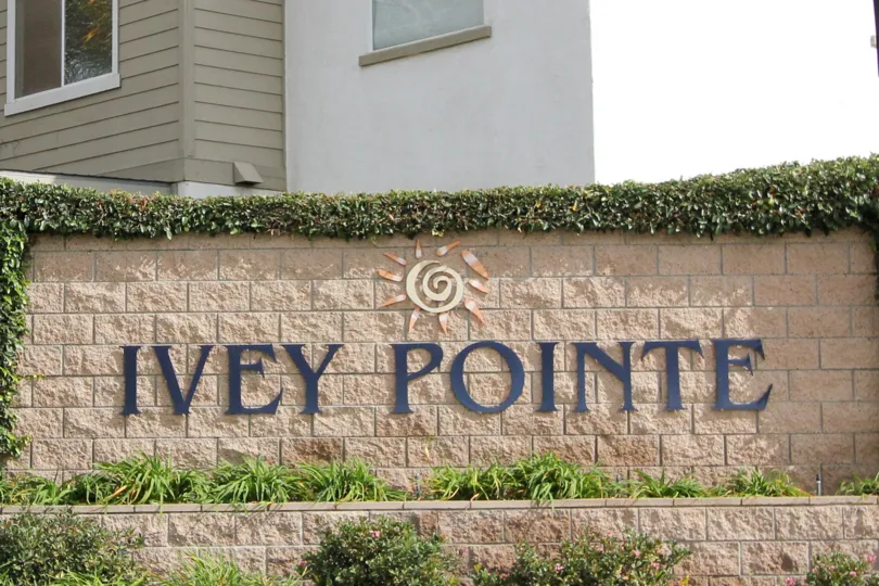 A sign for Ivey Pointe with a logo and decorative plants in Oceanside, CA