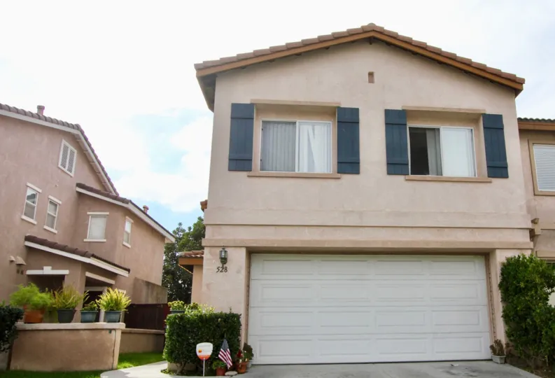 A house with a garage and a small flag at Ivey Pointe in Oceanside, CA