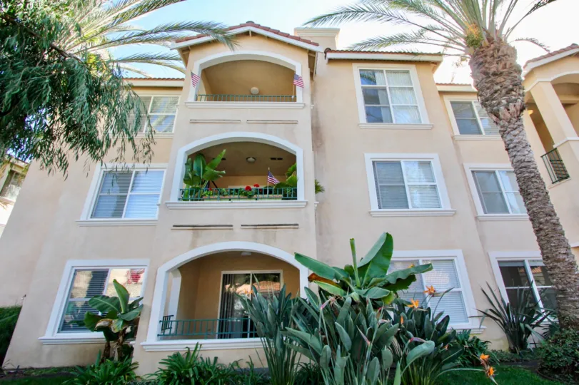 Three story building with tropical landscaping and porches at La Costa Villas in Oceanside, California