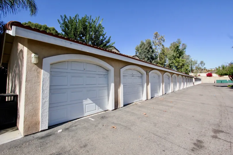 A sunny day in the area of La Costa Villas, outside, parking lot, garage, trash can, bush, tree