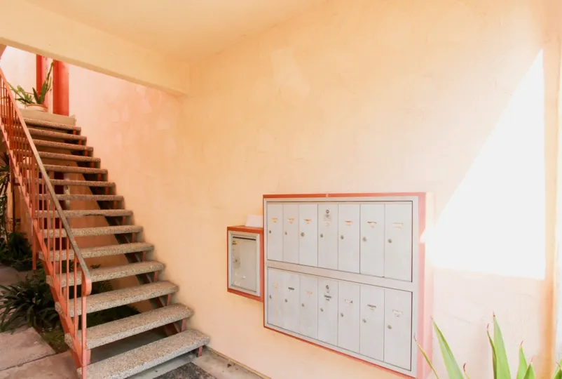 Silver mail boxes on a pink wall near stairs at La Montana in Oceanside CA