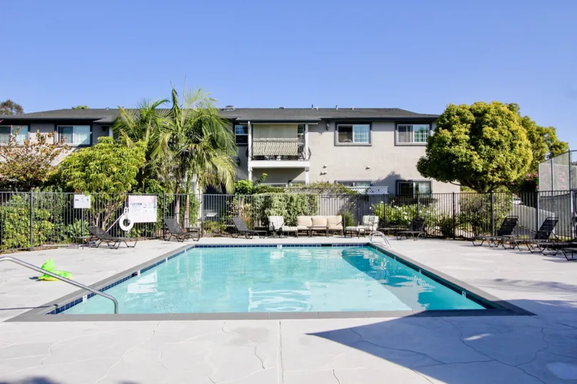 pool inside housing area with greenery and kid toys around