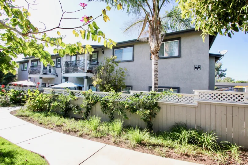 Gray condo homes behind a gray & white fence at Las Brisas in Oceanside CA