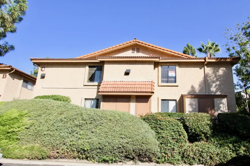 An independent house with red tiles and windows surrounded by a lush green bushes at Loma Alta Village